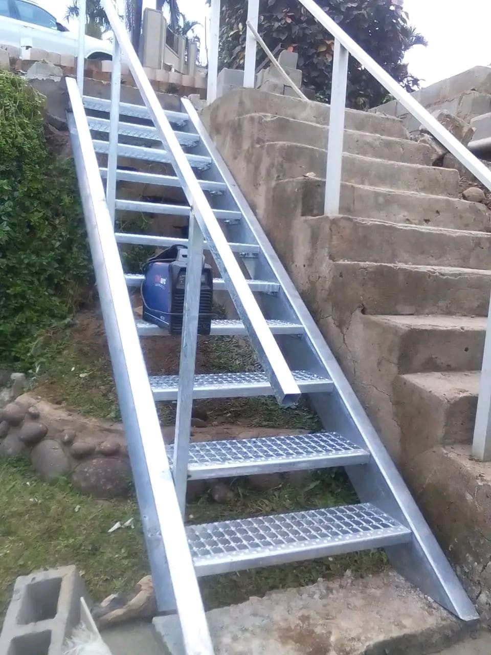 Galvanised steel access staircase built into a sloped garden