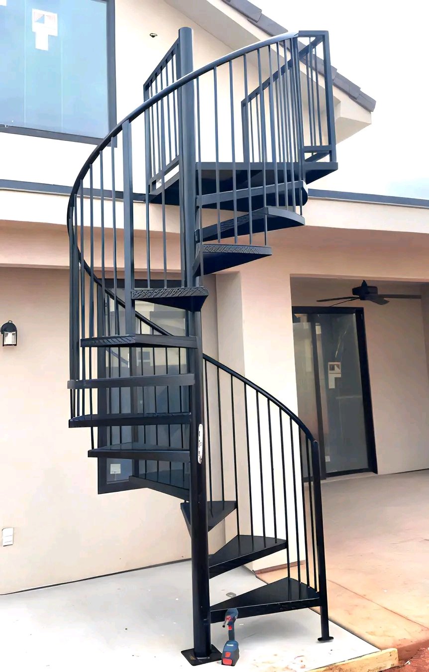 Black spiral staircase in a paved courtyard