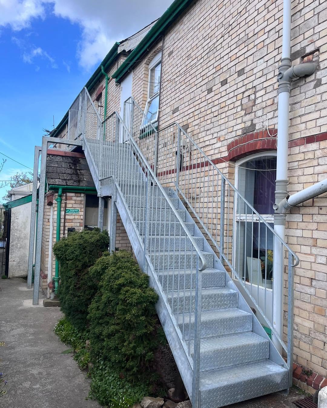 Galvanised exterior staircase and landing on a brick facade